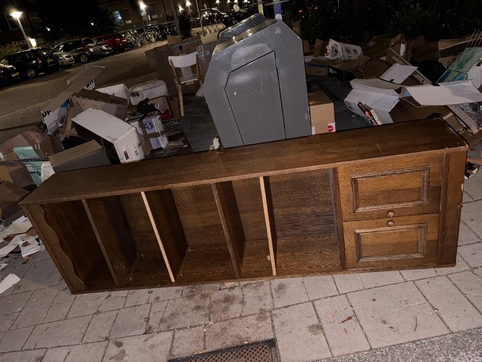 Ligt op zn kant. Het is een hoge kast en de deurtjes rechts betreft de onderkant.