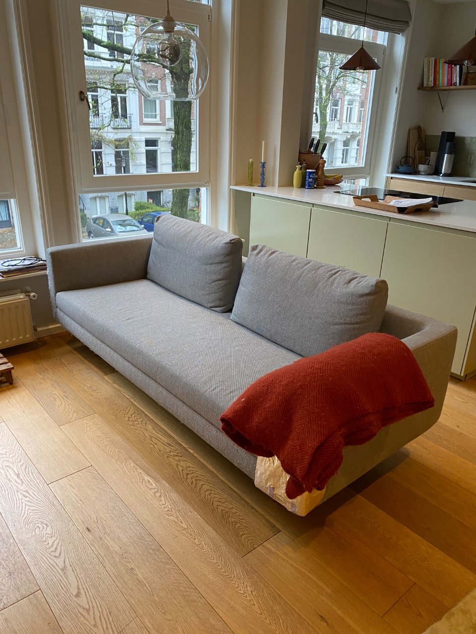 Grijze bank, 220cm lang, kattenkrabsporen en lichte vlek in zitting